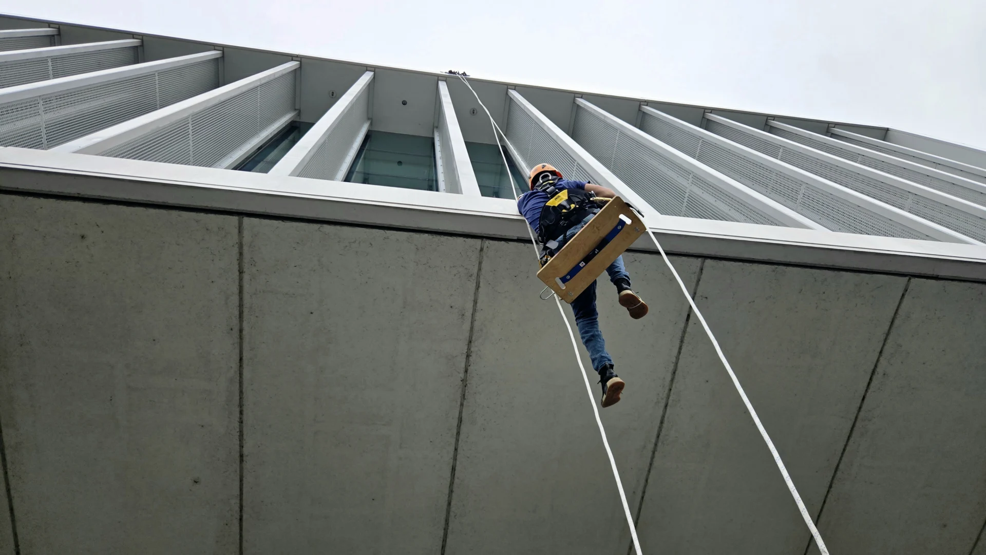 Commercial and Industrial Power Washing technician rappelling down a building.