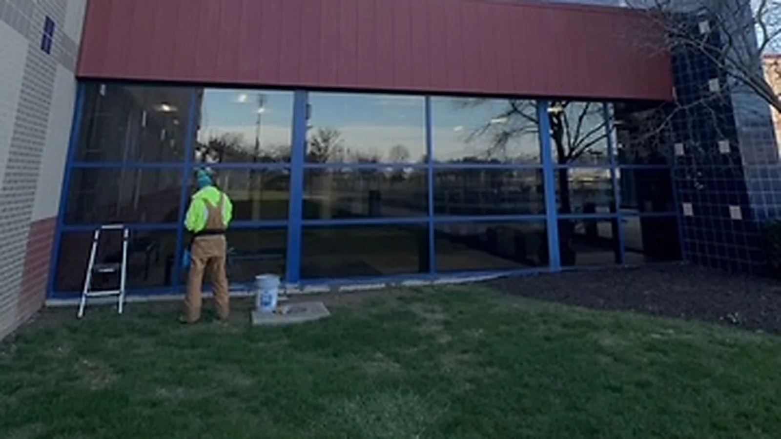 A Walden technician cleaning a storefront glass wall at Hamilton Southeastern High School